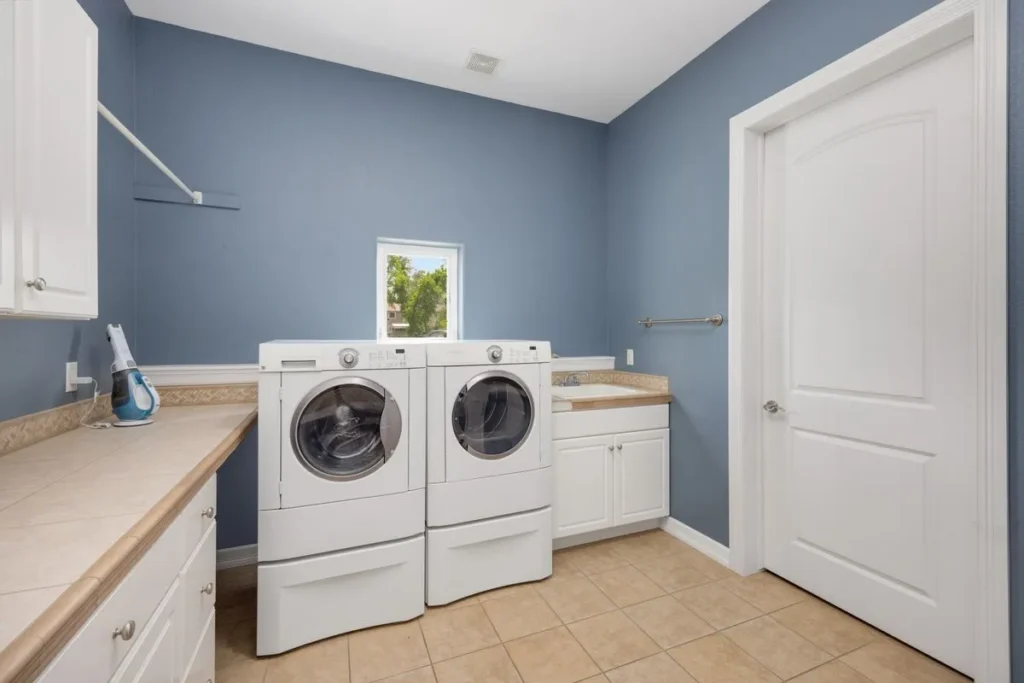 Laundry room with a white washer and dryer under a window