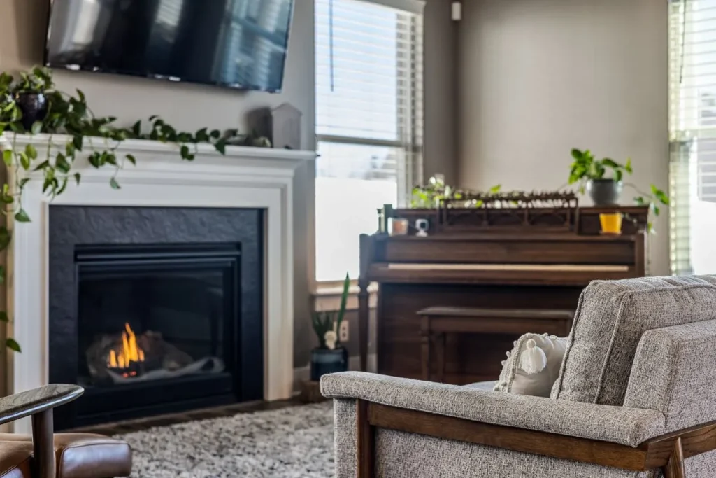 Living room with a lit fireplace in a white mantel next to a piano