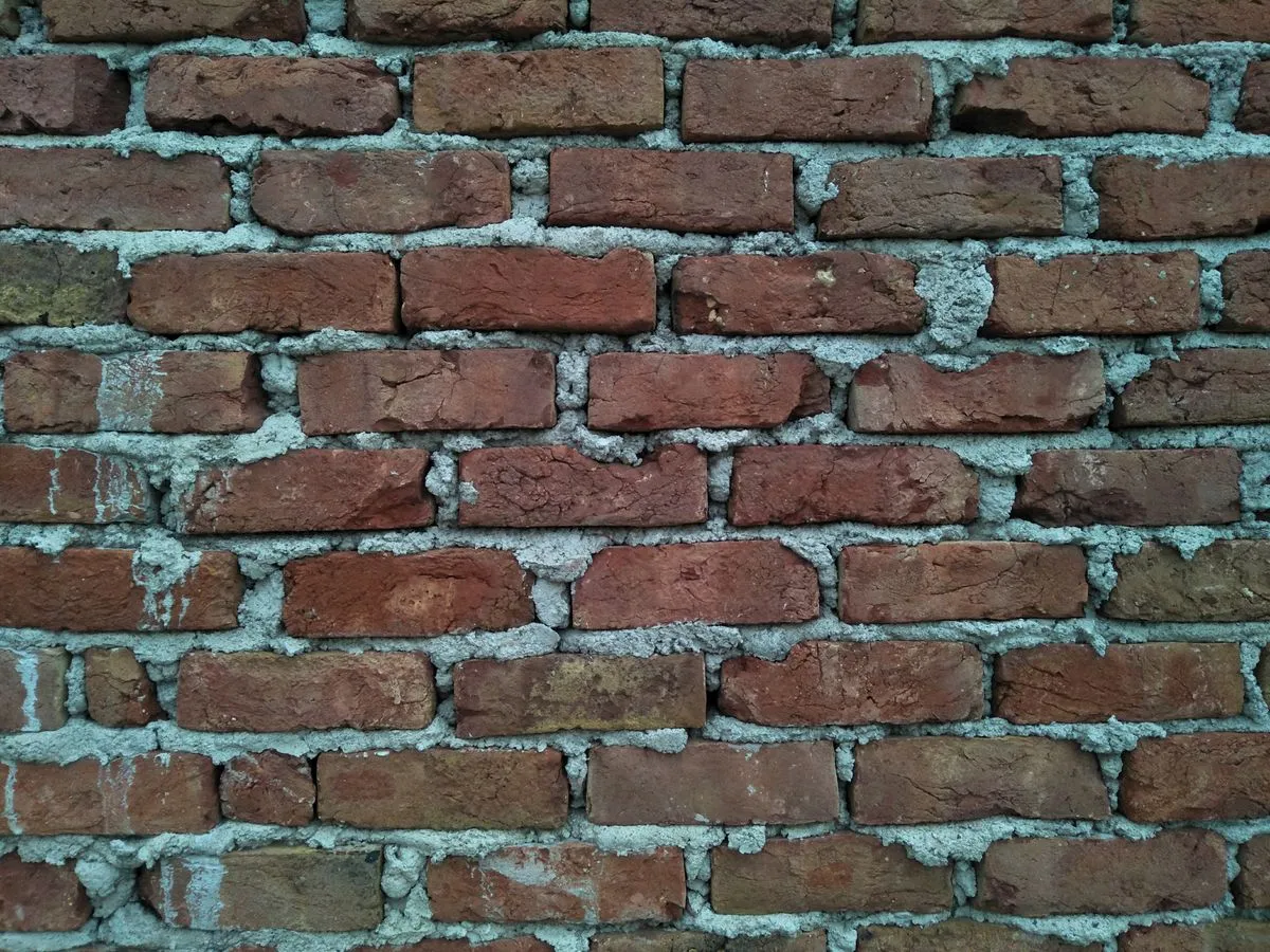 Old red brick wall with gray mortar joints