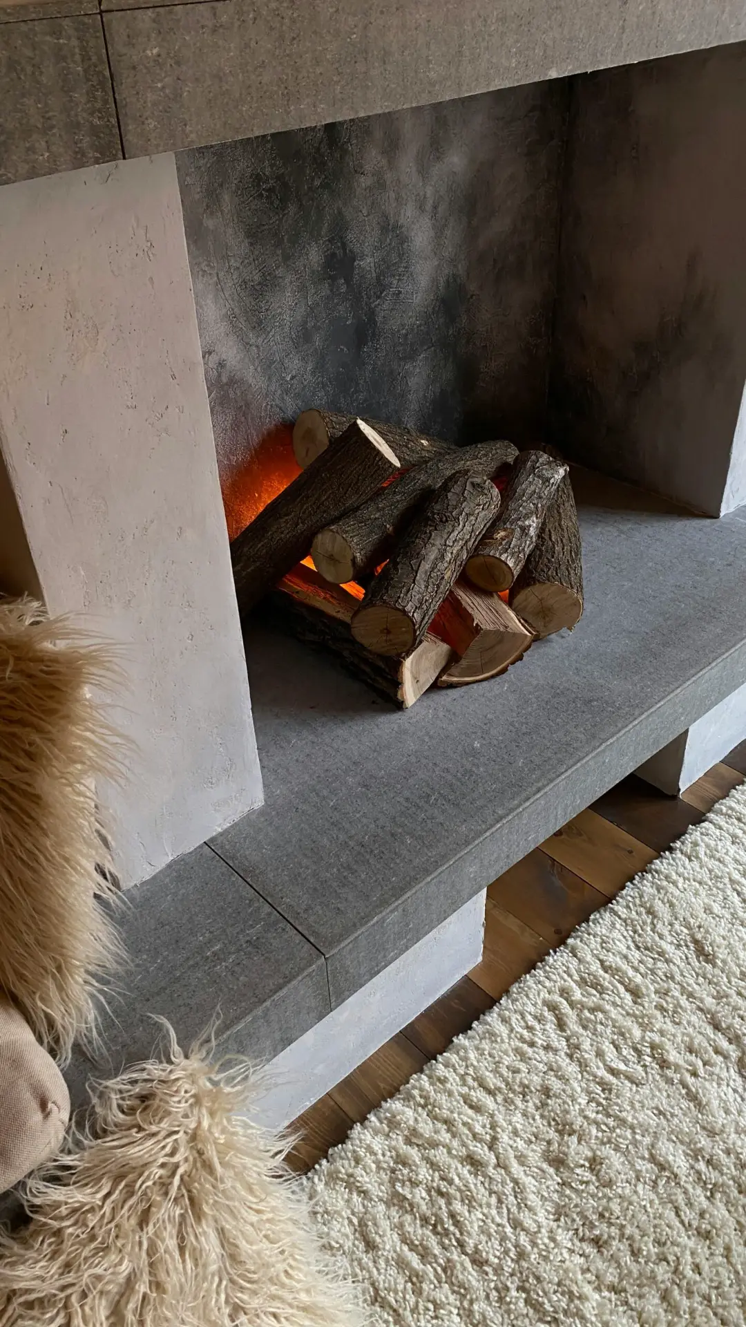 Firewood logs in a modern fireplace with a gray stone hearth