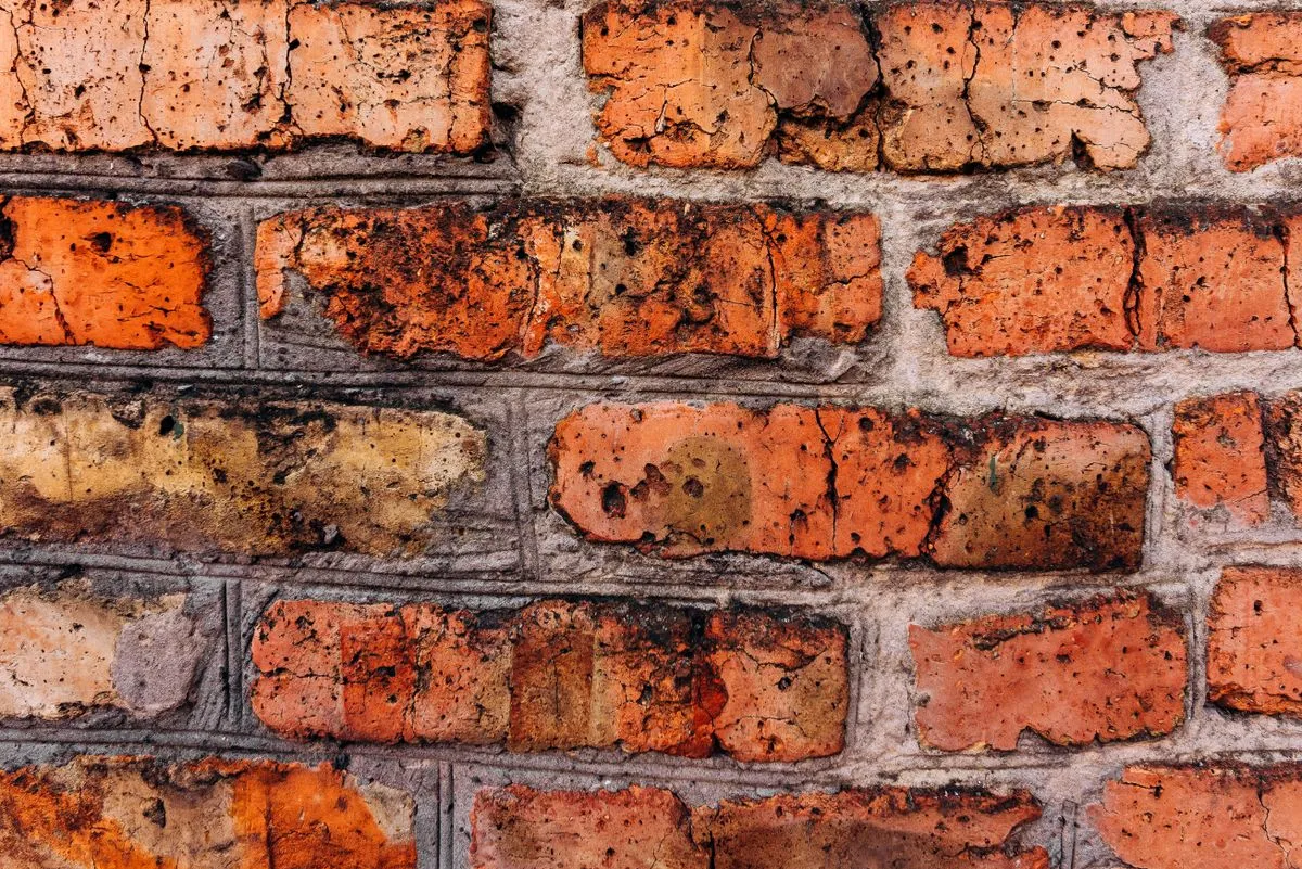Close-up of worn red brick with eroded faces